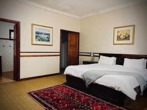 a bedroom with a large bed and a red rug at Phumulani Lodge Kameeldrift in Pretoria
