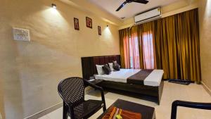 a bedroom with a bed and a chair in a room at Shivalay Premium Homestay in Ujjain