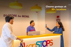 three people standing around a counter with a woman holding a cell phone at goSTOPS Plus Katra in Katra