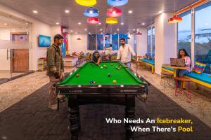 a group of people standing around a pool table at goSTOPS Plus Katra in Katra +46 photos