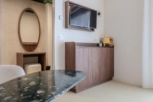 a living room with a table and a tv at Hotel Libera Spa et Restaurant Caen Colombelles in Caen