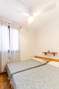 two beds in a white room with a window at Complejo turístico Menorca SOL ISLA in Arenal d'en Castell
