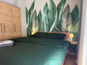 a bedroom with a green bed with a mural of leaves at Kutnowska Perła in Kutno