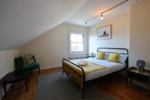 a bedroom with a bed and a chair and a window at Suffolk Coast Townhouse in Pakefield