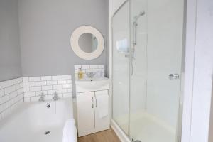 a white bathroom with a sink and a shower at Suffolk Coast Townhouse in Pakefield +46 photos