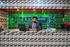 a man sitting at a desk with a laptop at Al Hera Resort in Sreemangal