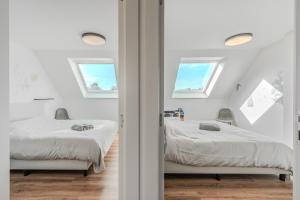 two beds in a white room with two windows at vakantiewoning T'is ier goed in Jabbeke +62 photos