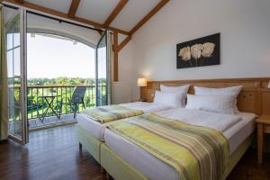 a bedroom with a large bed and a balcony at Golfpark Strelasund in Süderholz