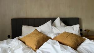 a bed with white sheets and two brown pillows at hellofrom Tobacco Warehouse in Kavála