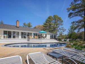 a house with a swimming pool and lounge chairs at Bayside The Point in Saint Michaels