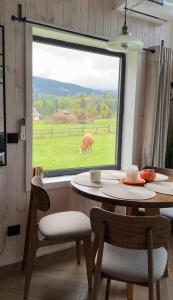a table with chairs and a cow outside a window at Osho house Karpaty in Ilʼtsya Dolishna