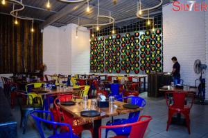 a restaurant with wooden tables and colorful chairs at Hotel Silver Seven in Jāmb