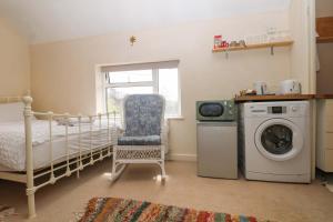 a bedroom with a bed and a washing machine at Daisy Cottage in Dorking