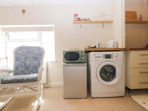 a kitchen with a washing machine and a chair at Daisy Cottage in Dorking +7 photos