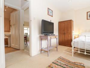 a bedroom with a television on a table with a bed at Daisy Cottage in Dorking