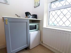 a kitchen with a microwave on top of a refrigerator at Daisy Cottage in Dorking