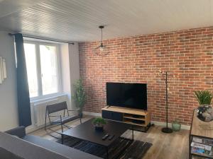 a living room with a brick wall and a flat screen tv at La Factory Saint Aignan in Saint-Aignan