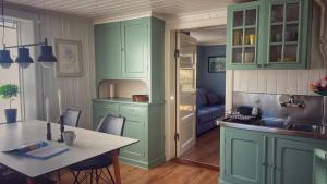 a kitchen with mint green cabinets and a table with a tableablish at Charmig lägenhet nära Smögenbryggan in Smögen