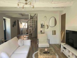 a living room with a white couch and a tv at La Stracciatella Saint-Aignan in Saint-Aignan