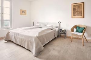a white bedroom with a bed and a chair at Hay Loft - Flensburger Förde in Westerholz