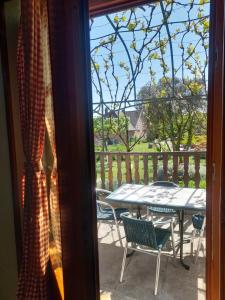 a table and chairs on a porch with a view of a yard at La Gloriette Riquewihr in Riquewihr