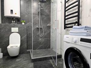 a bathroom with a shower with a toilet and a washing machine at Belvedere Apart, parking in Ivano-Frankivsk