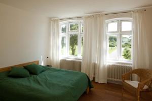 a bedroom with a green bed and two windows at Lake View - Flensburger Förde in Westerholz