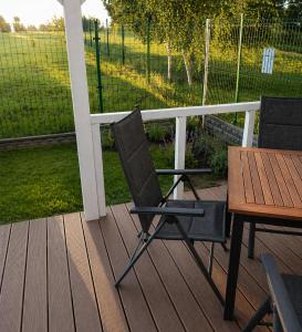 two chairs and a table on a deck at Domki 7 Houses Rewal in Rewal