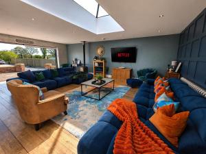 a living room with blue couches and a tv at The Stables Luxury House with Hot tub in York