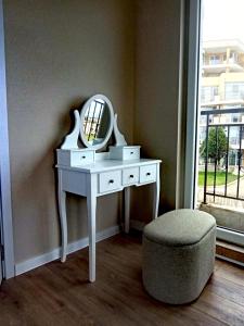 a white dressing table with a mirror and a stool at DL Apartments in Aheloy