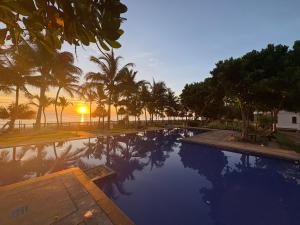 a swimming pool with palm trees and a sunset at Luxury Penthouse, Beachfront, Nilaveli in Trincomalee