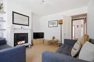 a living room with two blue couches and a fireplace at Coastguards in Southwold