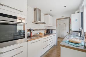 a kitchen with white cabinets and stainless steel appliances at Coastguards in Southwold