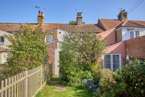 a row of houses with a fence and trees at Coastguards in Southwold