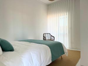 a white bedroom with a bed and a window at Salt Beach Apartments B in Viana do Castelo