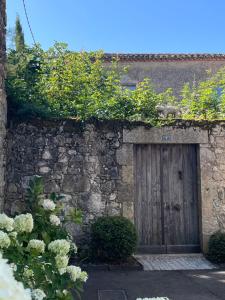 a stone building with a wooden door and plants at couleurs d'ici in Fleurance