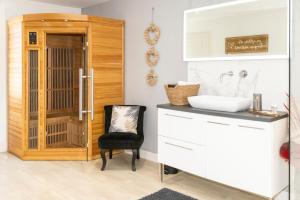 a bathroom with a sink and a chair at Le Carpe Diem - Détente & Bien-être - Balnéo, Sauna, CLIM, Terrasse, Parking privé in Dole