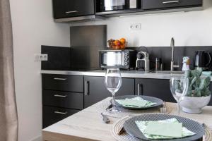 a kitchen with a table with two wine glasses at Le Carpe Diem - Détente & Bien-être - Balnéo, Sauna, CLIM, Terrasse, Parking privé in Dole