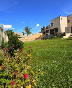 a field of grass with flowers in front of a building at Casa Parque Rio Uruguay in Concordia