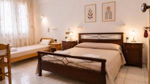 a bedroom with two beds and a table and a chair at Argyroupolis Dimitris Rooms in Argyroupolis