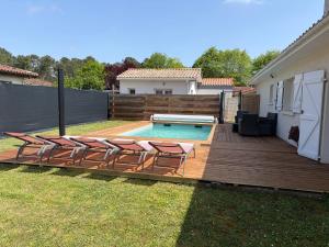 a deck with chairs and a pool in a backyard at Studio cosy avec piscine à 10 min Hossegor in Saint-Vincent-de-Tyrosse