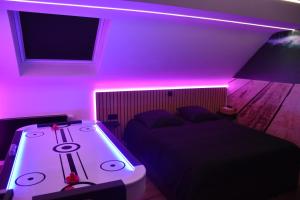 a bedroom with a bed with purple lights on it at Studio détente, sdb privative, billard, air soccer, clim in Verviers +24 photos