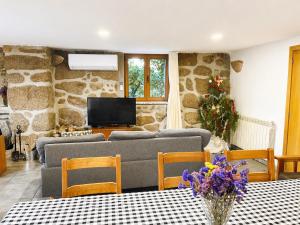 a living room with a couch and a tv at Casa da Lage - Piscina privada - Vistas rio - "Gerês" in Geres