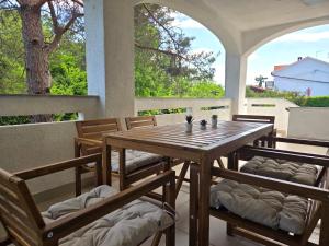a wooden table and chairs on a porch with windows at Apartman Filip in Risika +19 photos