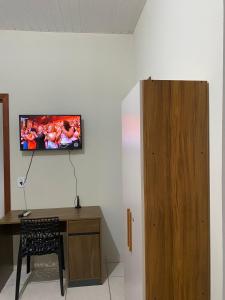 a room with a desk and a tv on the wall at Aconchego da Si AP in Nova Mutum