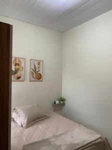 a bedroom with a bed and three pictures on the wall at Aconchego da Si AP in Nova Mutum