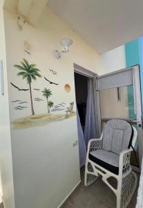 a chair in a room with a palm tree on the wall at A pasos de la playa y el centro de Bayahibe in Bayahibe
