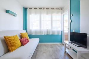 a living room with a white couch and a television at Apartamentos Eldorado in Lloret de Mar