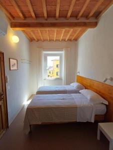 two beds in a room with a window at Appartamenti - AL4 in Guardistallo
