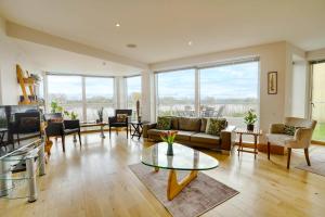 a living room with a couch and a table at Squirrels Leap Lake Views with Spa Access, Lower Mill Estate in Somerford Keynes